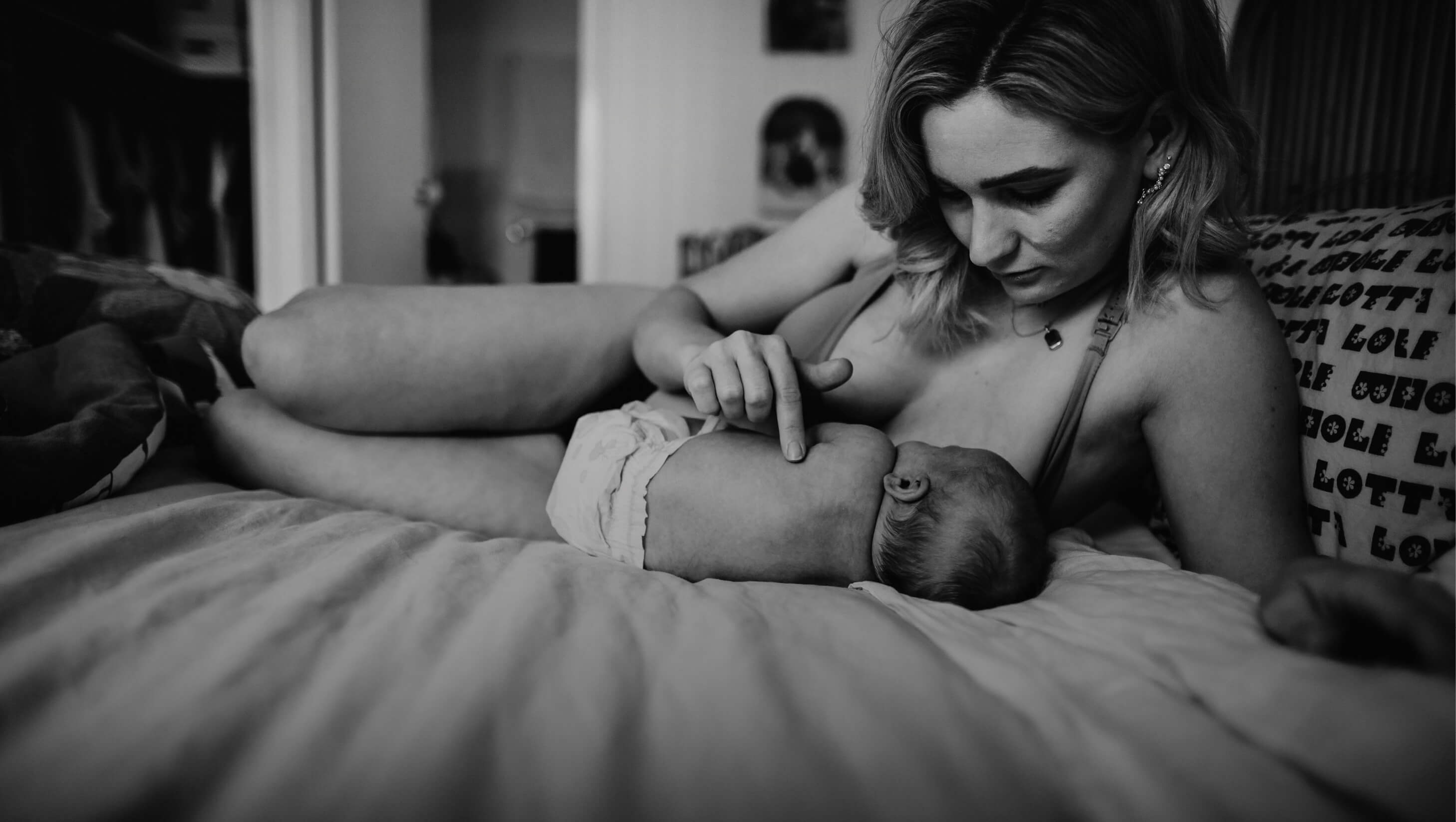 woman breastfeeding baby on bed