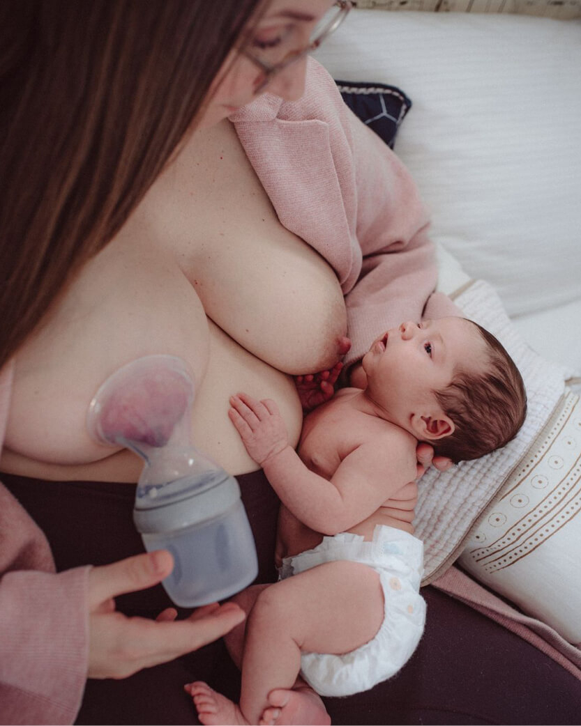 woman breastfeeding baby while pumping