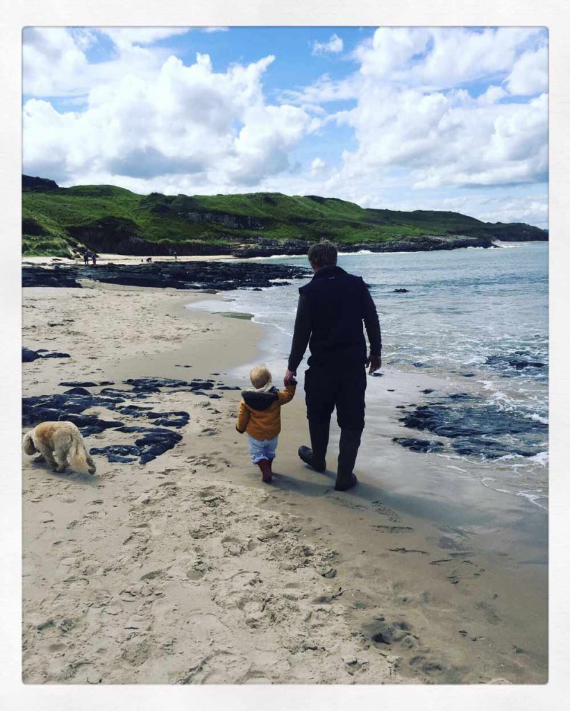 father and child walking at the beach