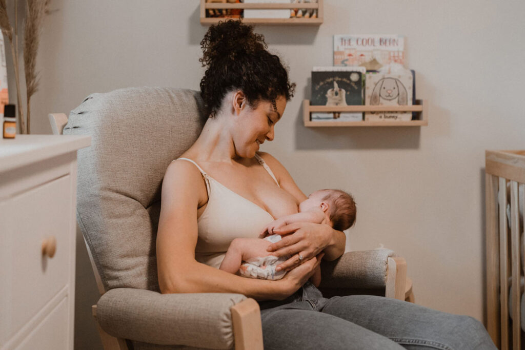 mother sitting on a chair, breastfeeding her baby.